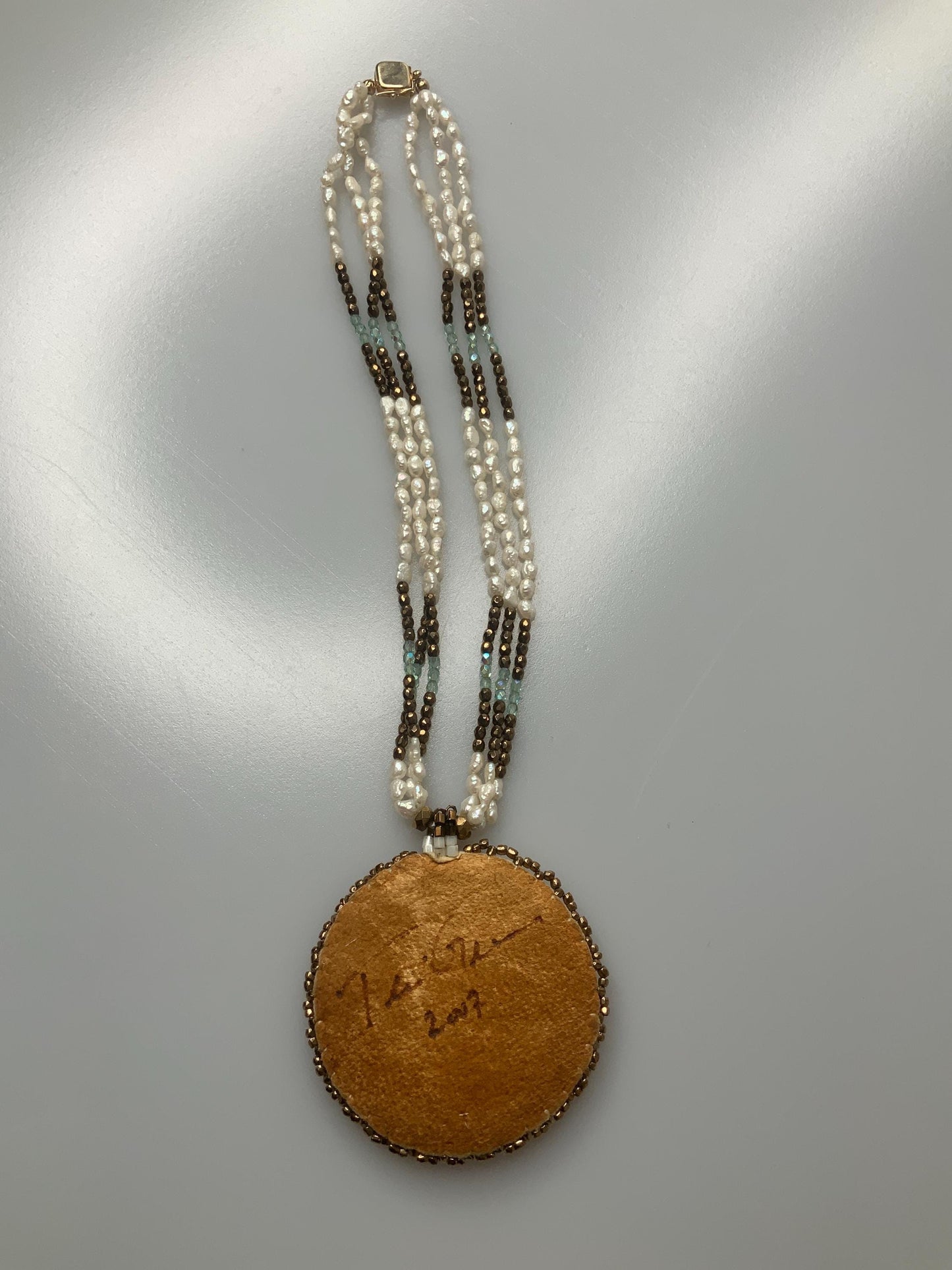 T.G. 2007 signed Turqoise beaded pendant on leather with three stands of pearls and other material beads with a open box 14k gold clasp.